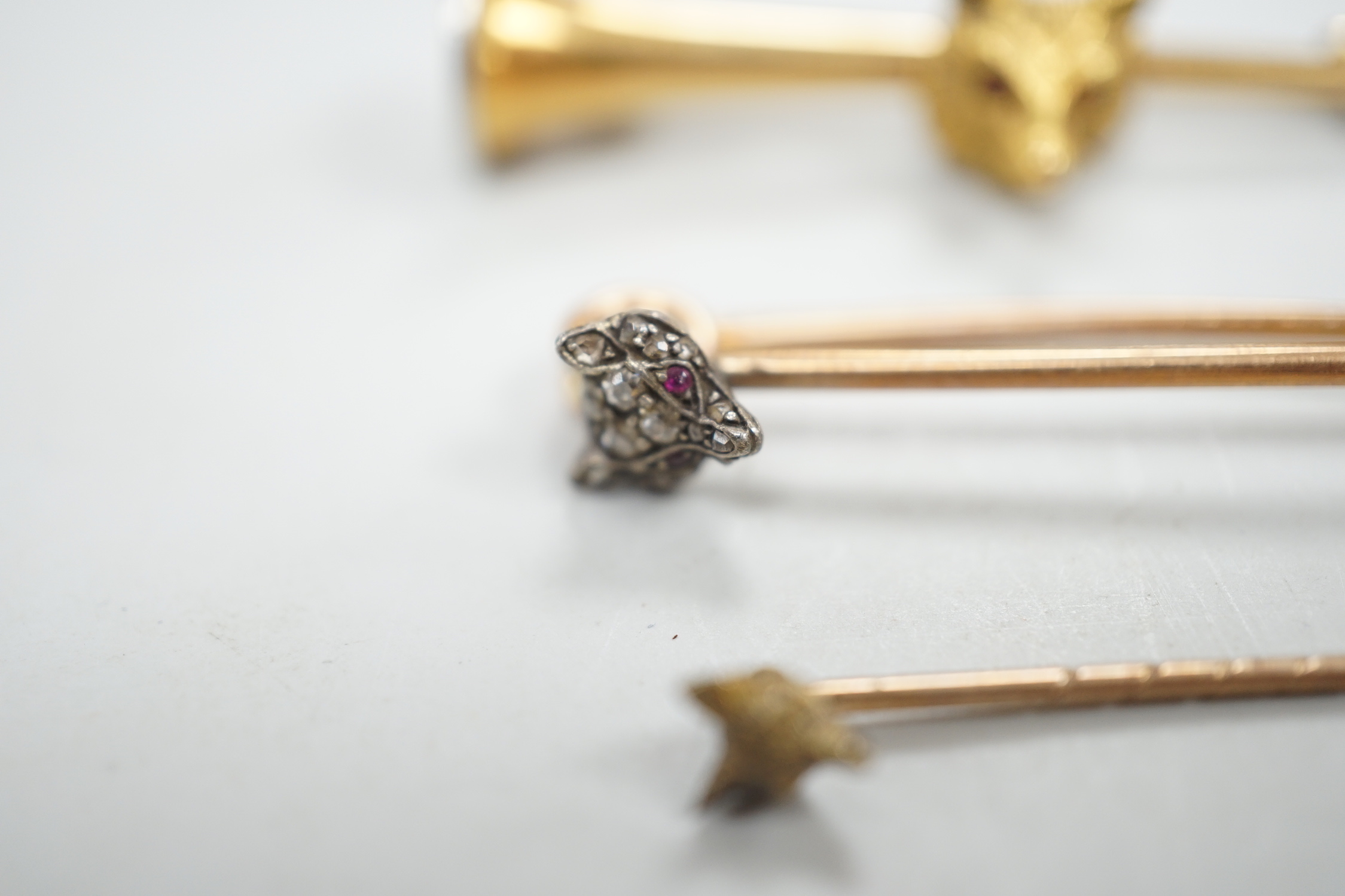 A Victorian yellow metal and diamond cluster set fox head pin, 44mm, two other fox head pins and a 15ct fox head and hunting horn brooch, gross weight 8.5 grams.